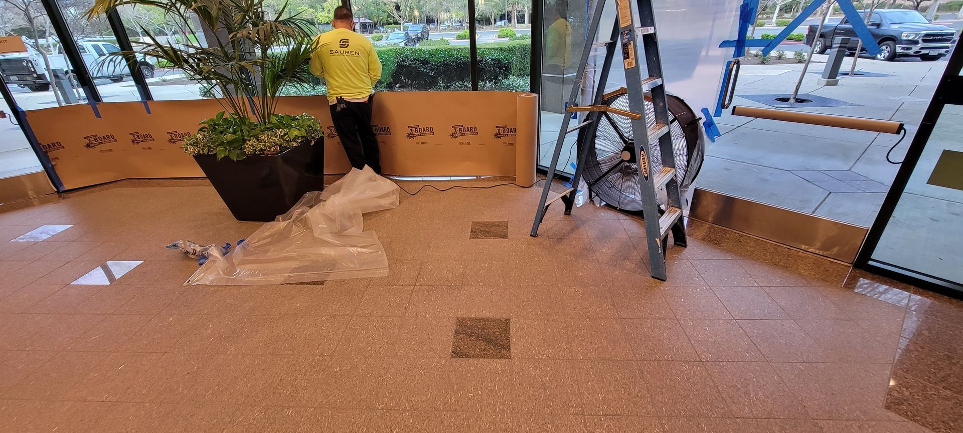 A man is standing in a room with a ladder and a potted plant.