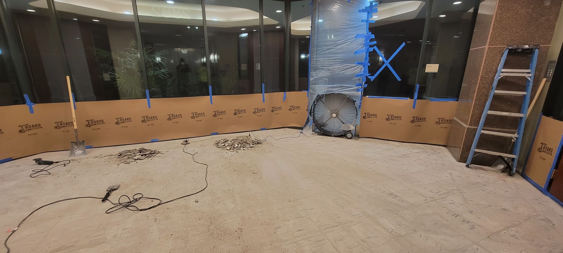 An empty room with a ladder and a fan in it.