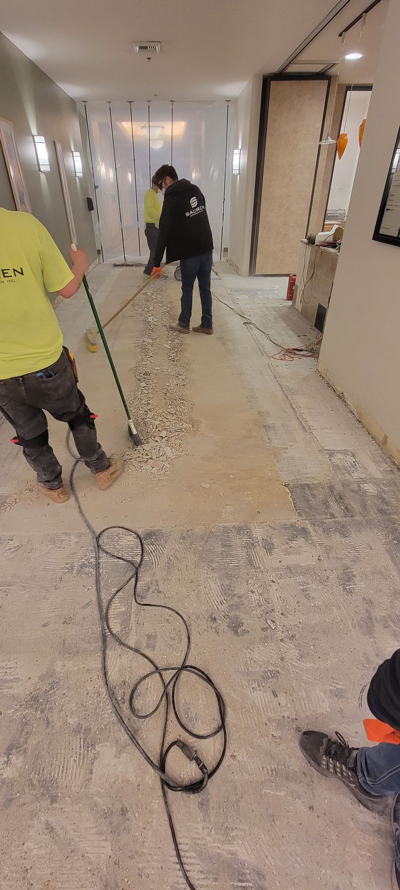 A group of construction workers are cleaning the floor of a building.
