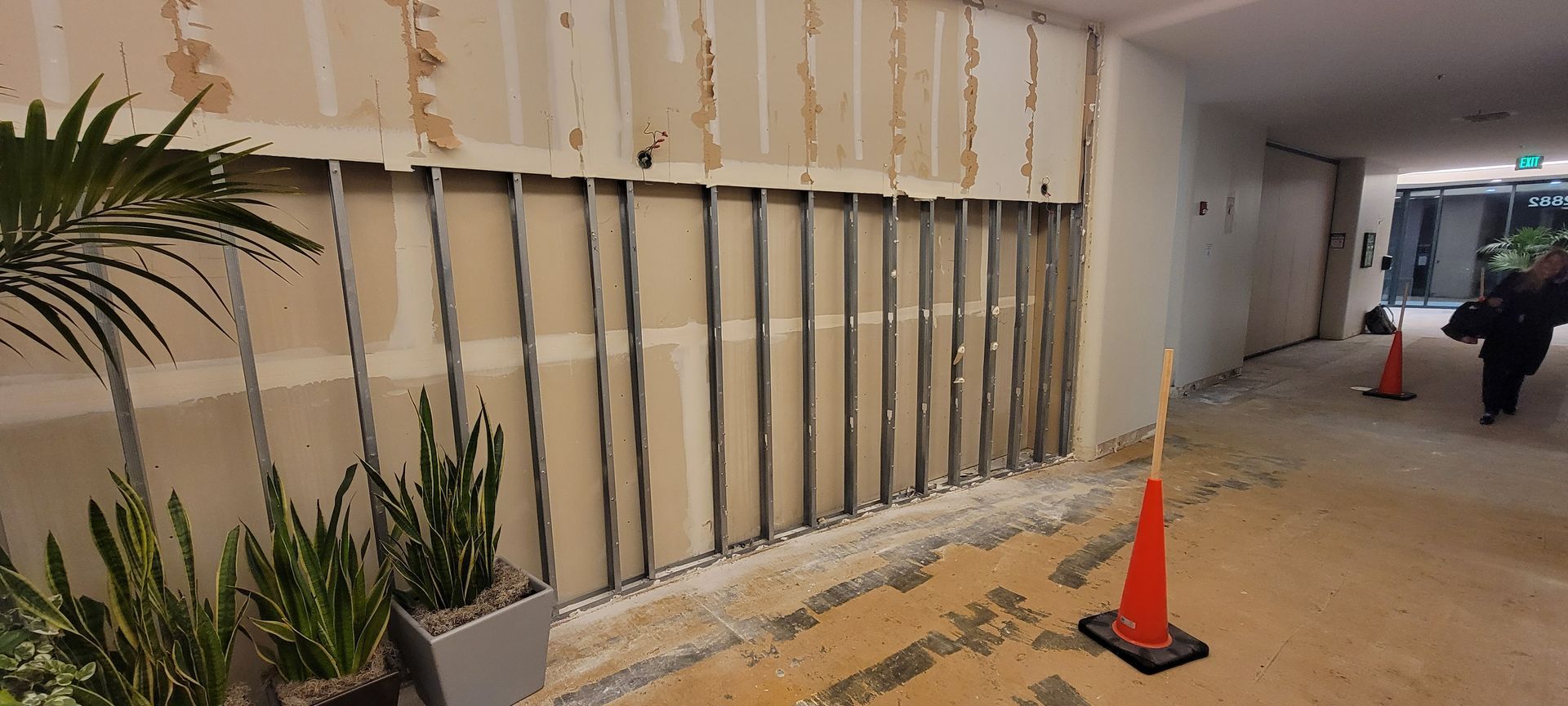 A person is walking down a hallway with cones and plants.