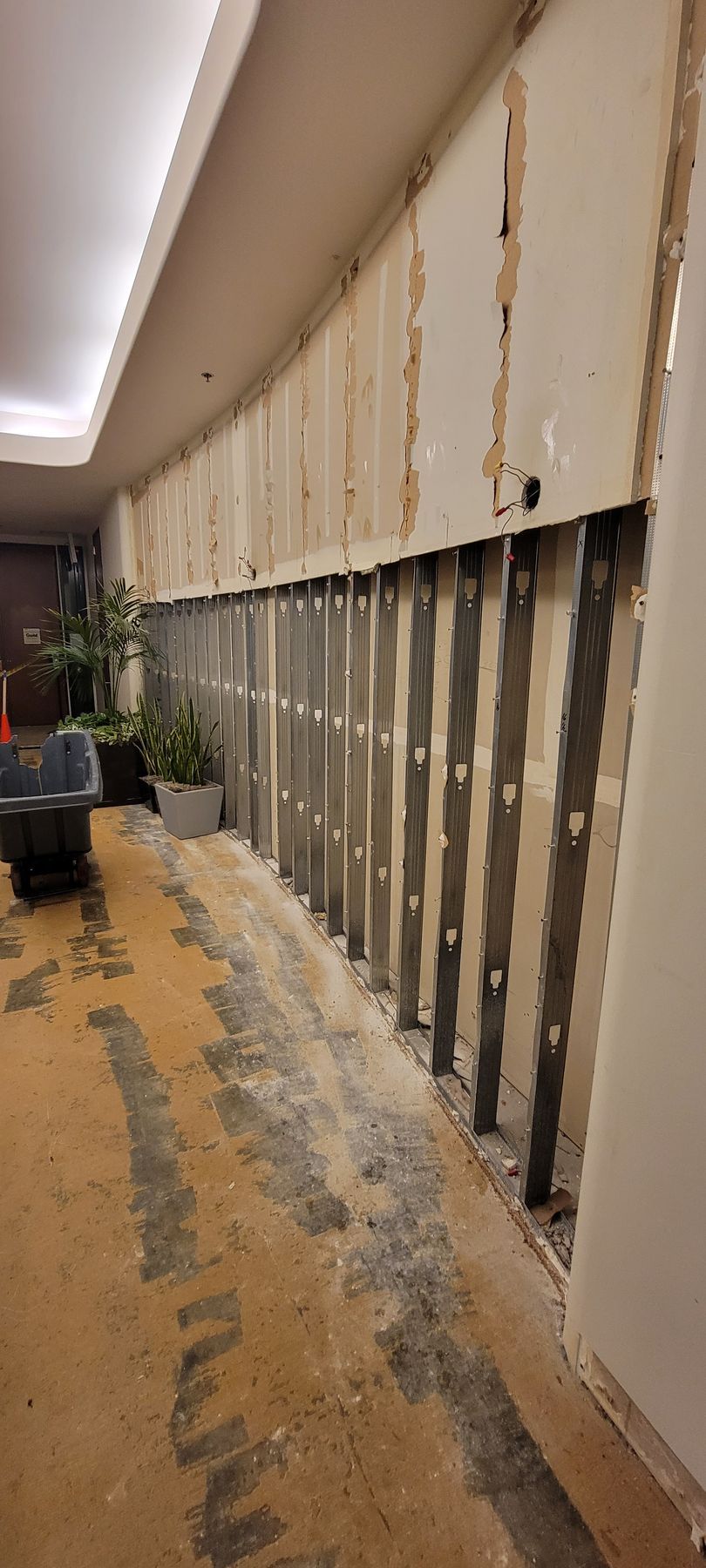 A hallway with a carpeted floor and a wall that is being remodeled.