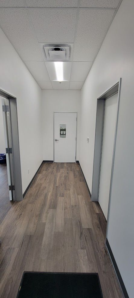 A long hallway with wooden floors and white walls.