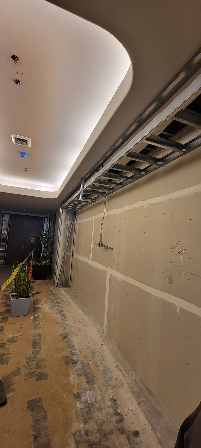 A person is standing in a hallway with a ladder hanging from the ceiling.