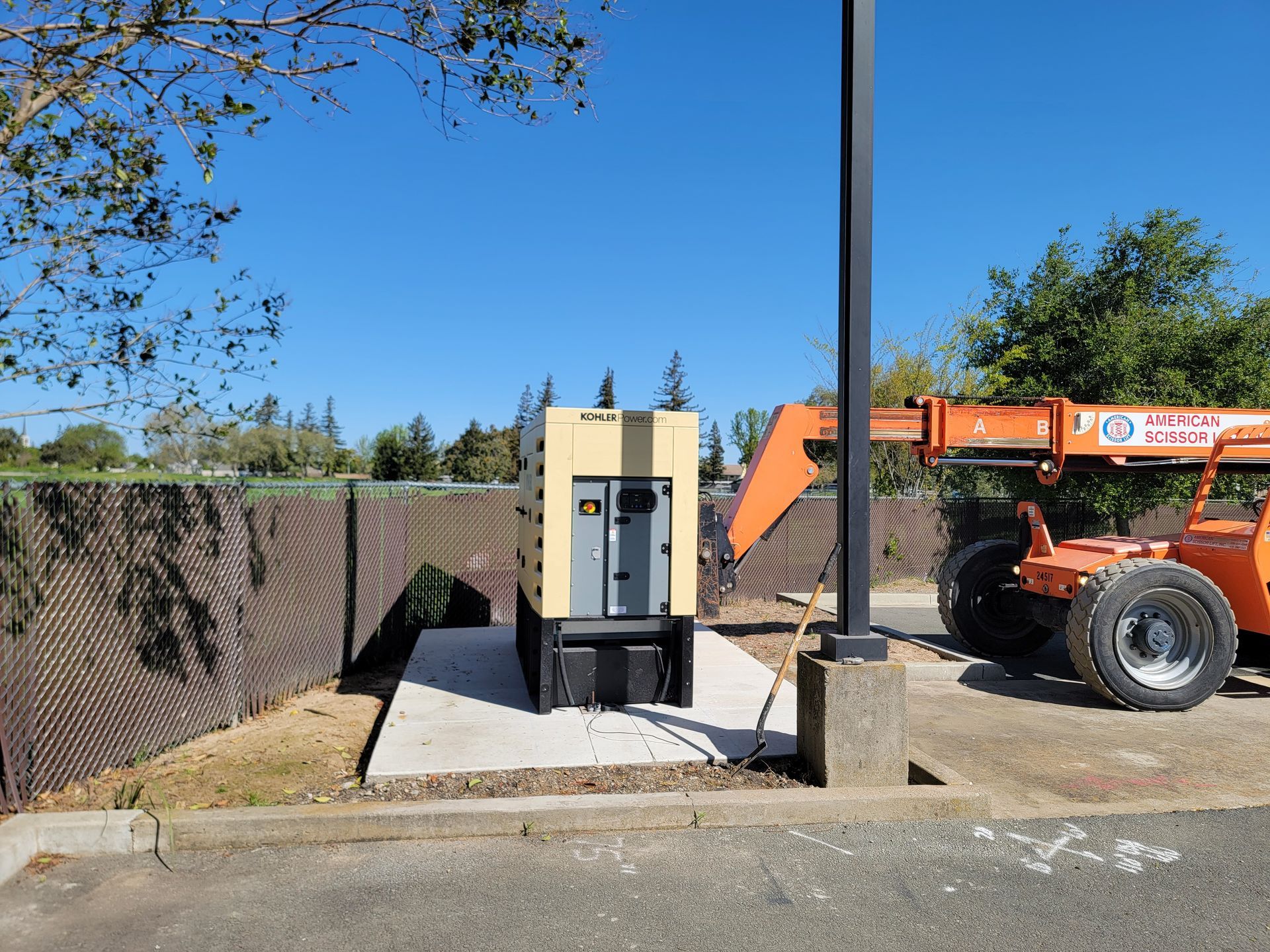 A tractor is parked next to a generator in a parking lot.