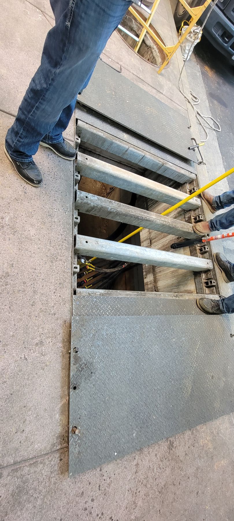 A man is standing next to a manhole cover on a sidewalk.