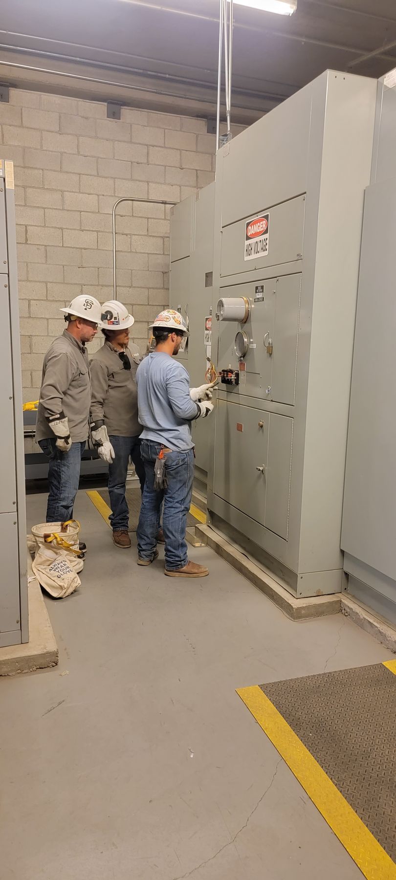A group of men are working on a control panel in a room.