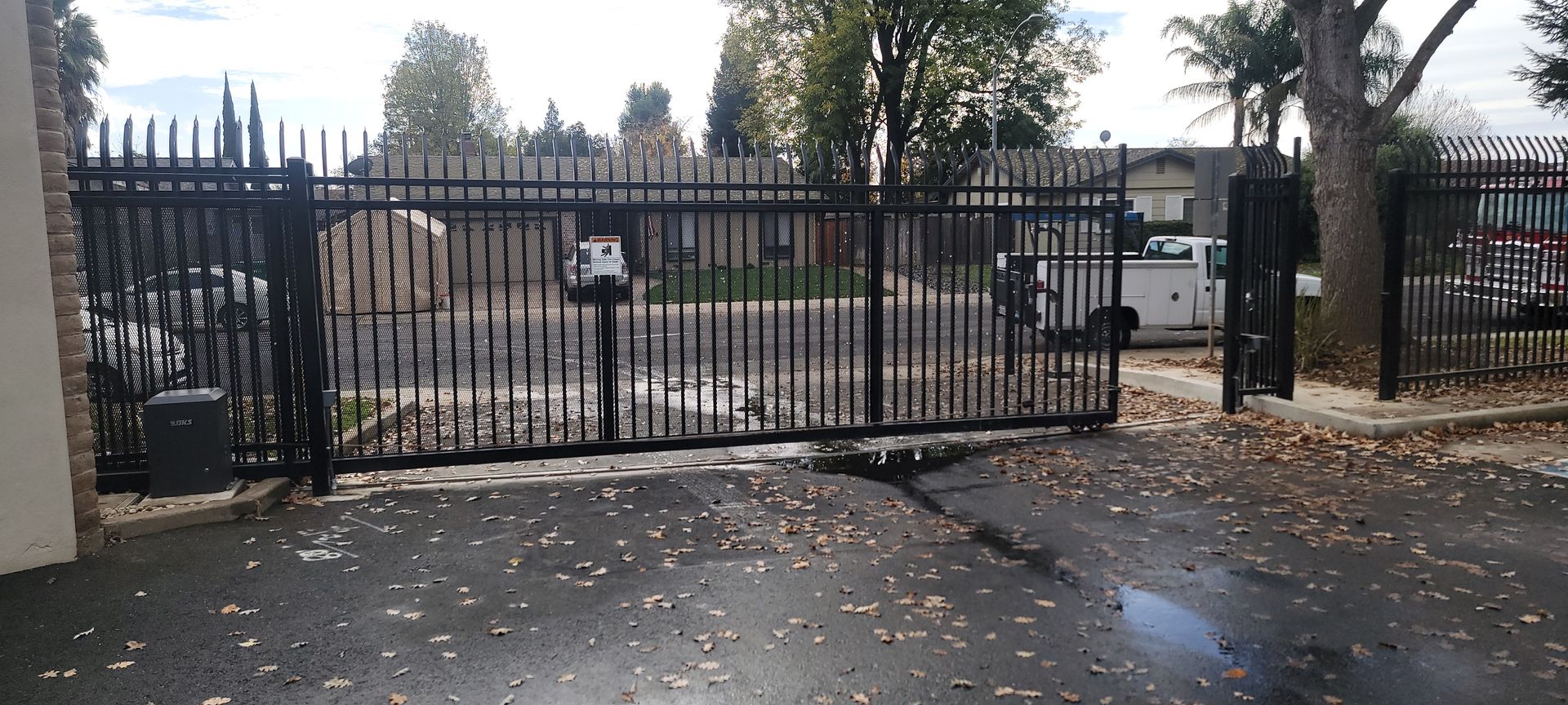 A sliding gate is open to a parking lot.