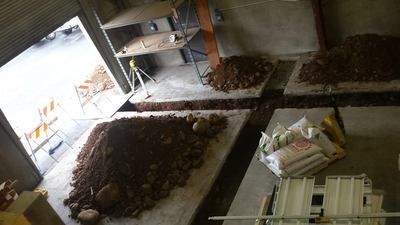 A pile of dirt is sitting on top of a concrete floor in a room.