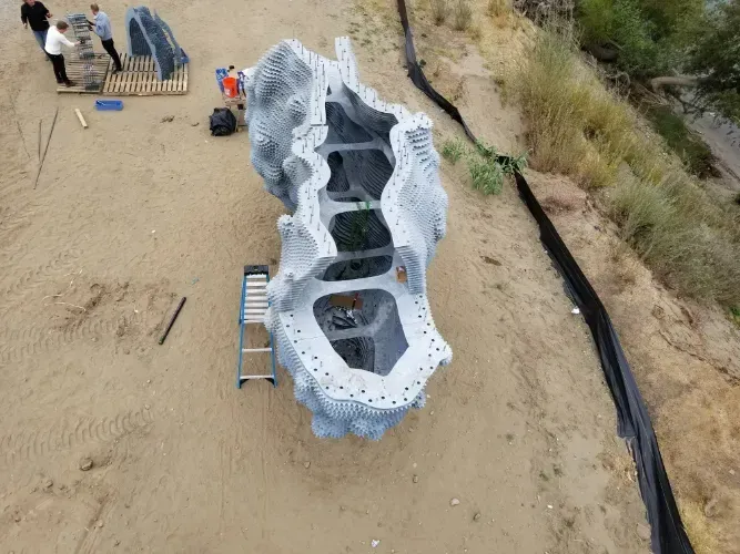 An aerial view of a large sculpture being built on a sandy beach.