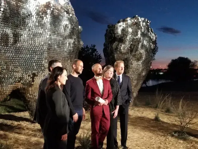 The team of Sauren Construction is standing in front of a sculpture.