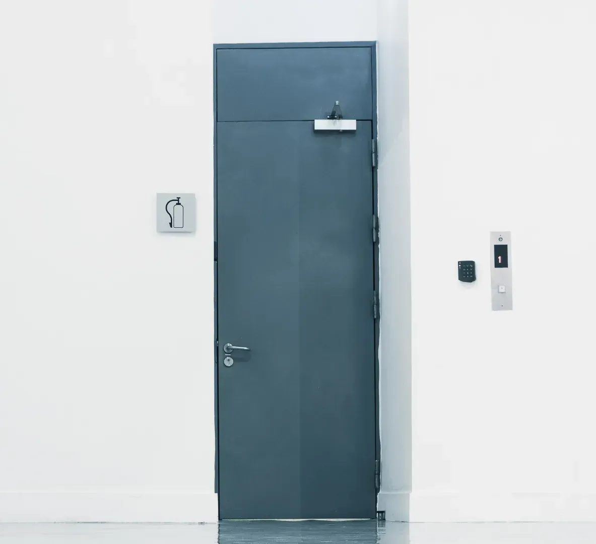 A black door with a sign on the wall above it.