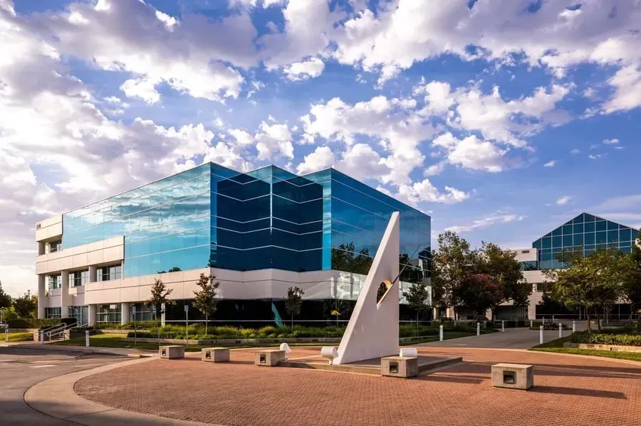 A large glass building with a sundial in front of it.