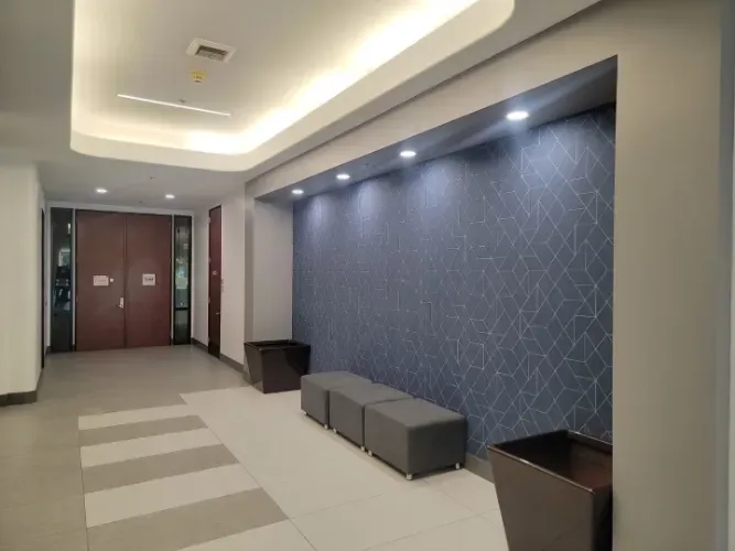 A hallway with a blue wall and a row of ottomans.