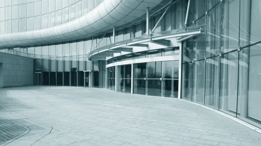 A large retail center with a lot of windows and a concrete walkway in front of it.