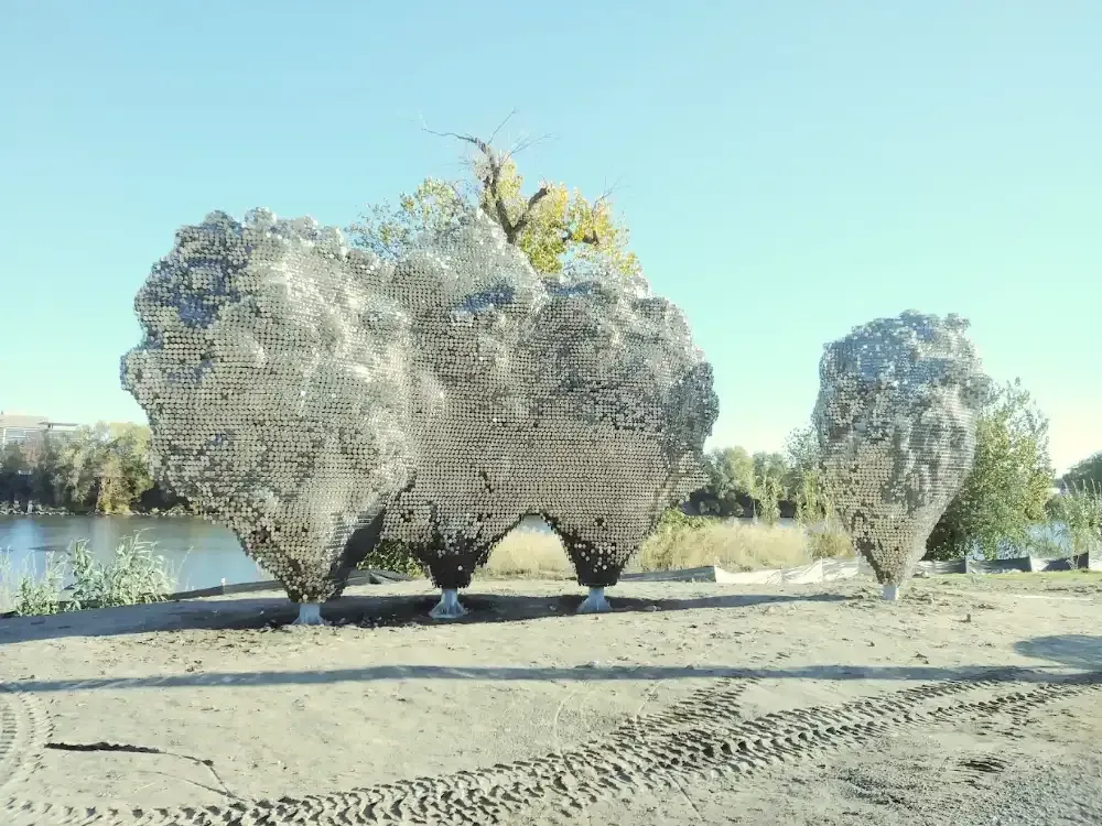 Two large rocks are sitting in the sand near a body of water