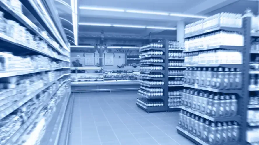 A blurred image of a supermarket aisle filled with lots of products.