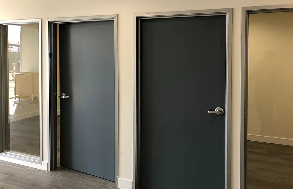 A hallway with three doors and a glass wall.