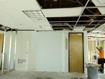 A man is working on the ceiling of an empty room.
