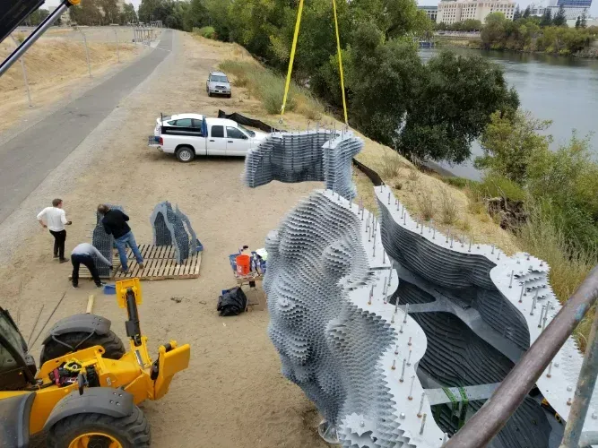 A large sculpture is being lifted into the air by a crane.