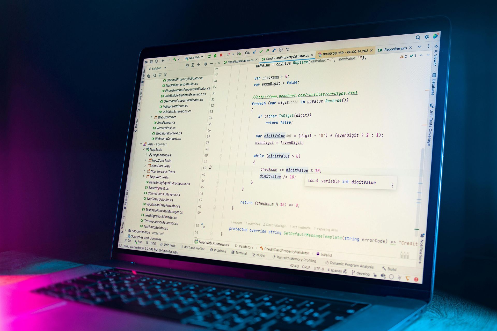 Laptop displaying code on a bright screen with neon pink and blue lighting around it