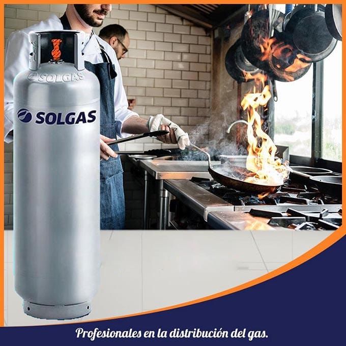 Tanque de propano Solgas plateado en una cocina, chefs cocinando con llamas.