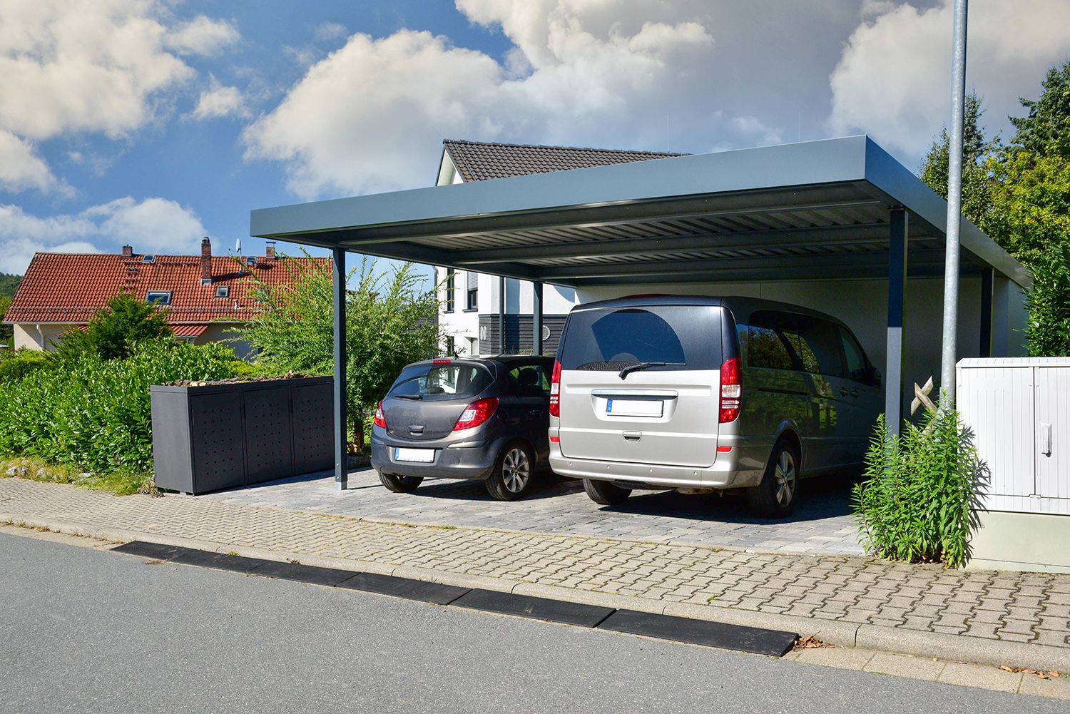 View of a modern, custom carport in a residential setting, covering two vehicles.
