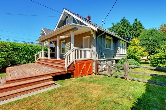 a house with a deck and a fence in front of it