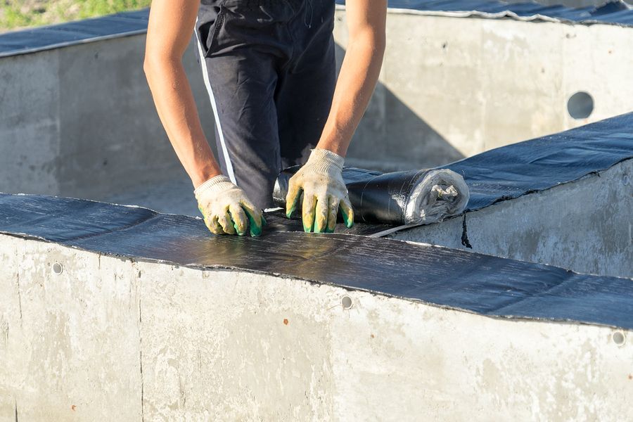 a man in black shirt and gloves working on a concrete structure