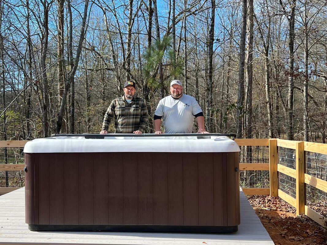 two men standing next to a hot tub in the woods