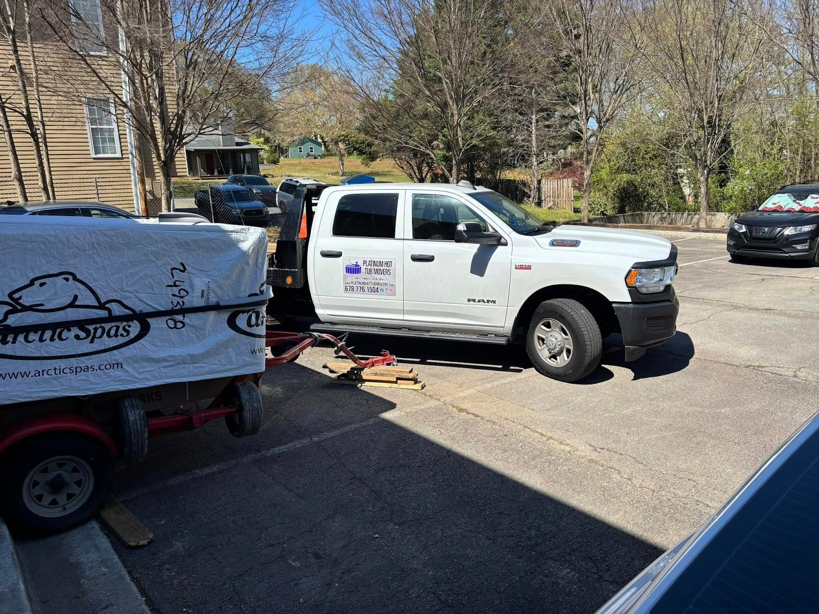 White work truck with trailer, parked in a lot, sunny day. Trailer covered in tarpaulin.
