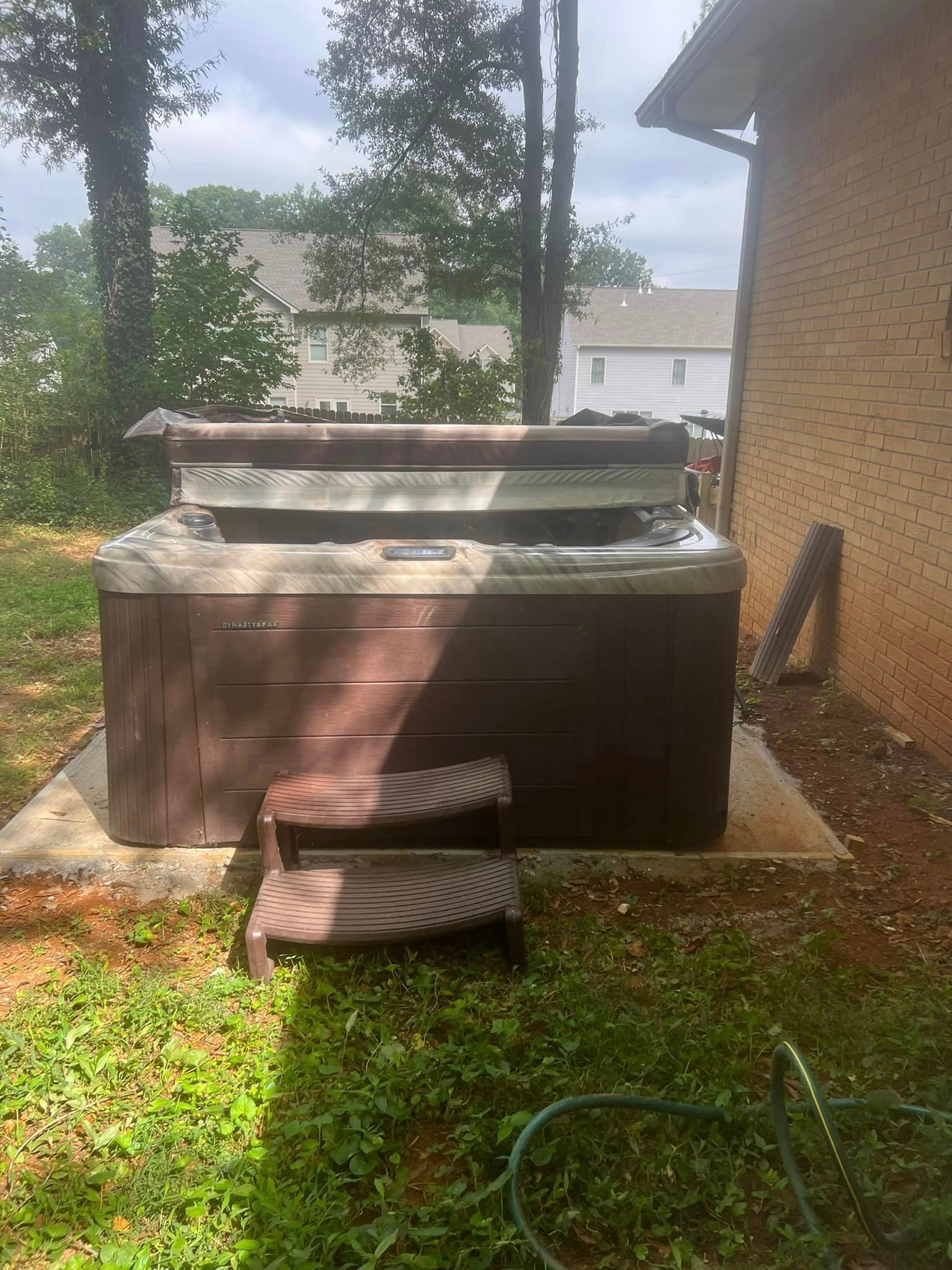 A hot tub is sitting in the backyard of a house.