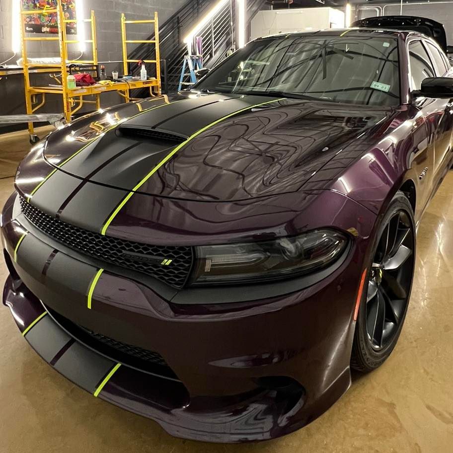 A purple dodge charger is parked in a garage