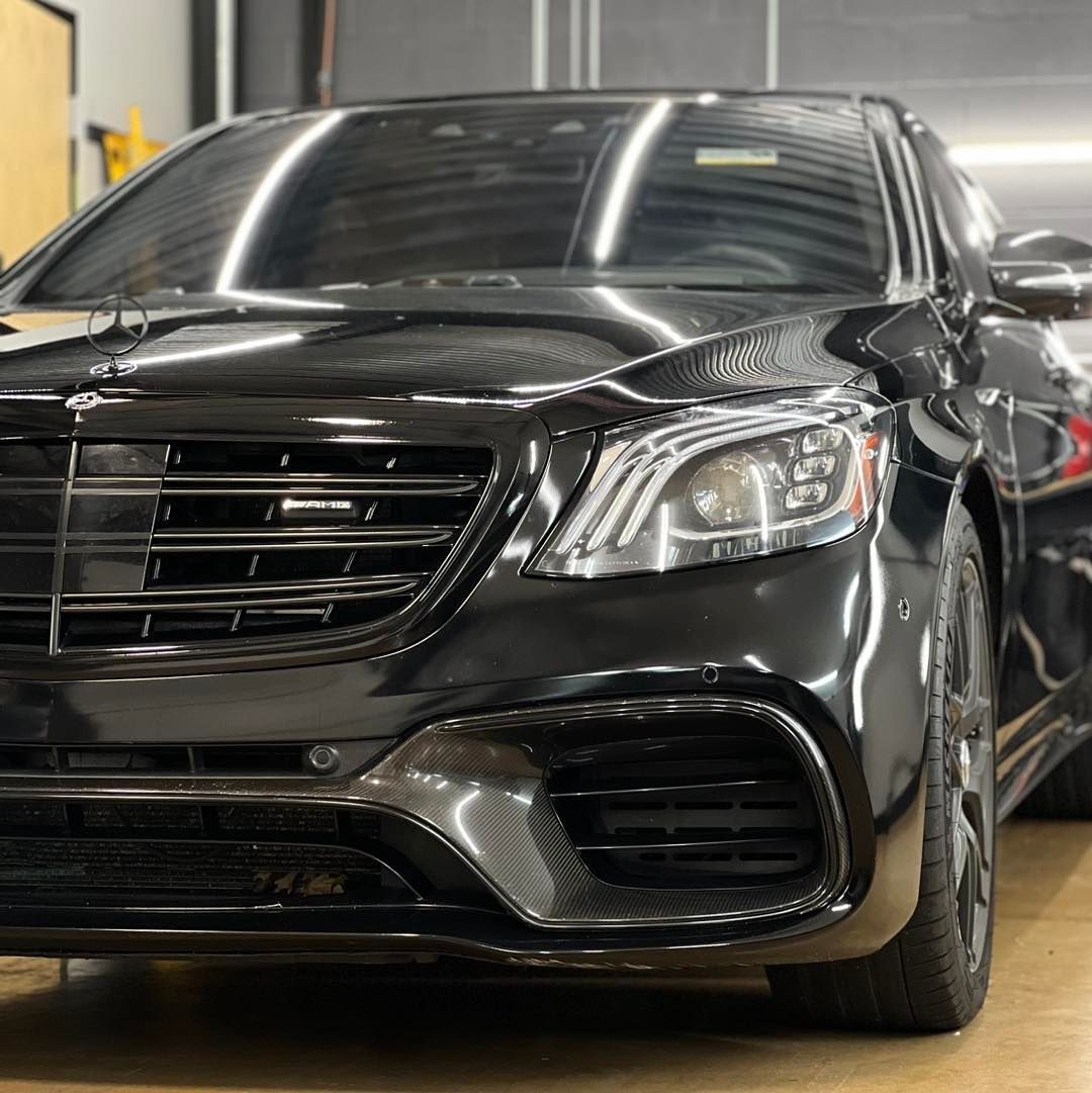 A black mercedes benz is parked in a garage