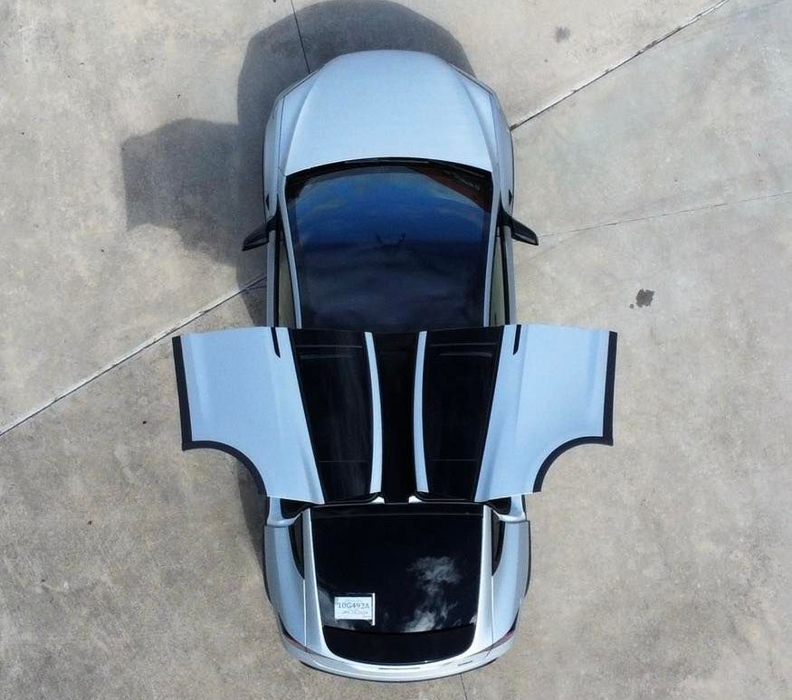 An aerial view of a silver car with its doors open