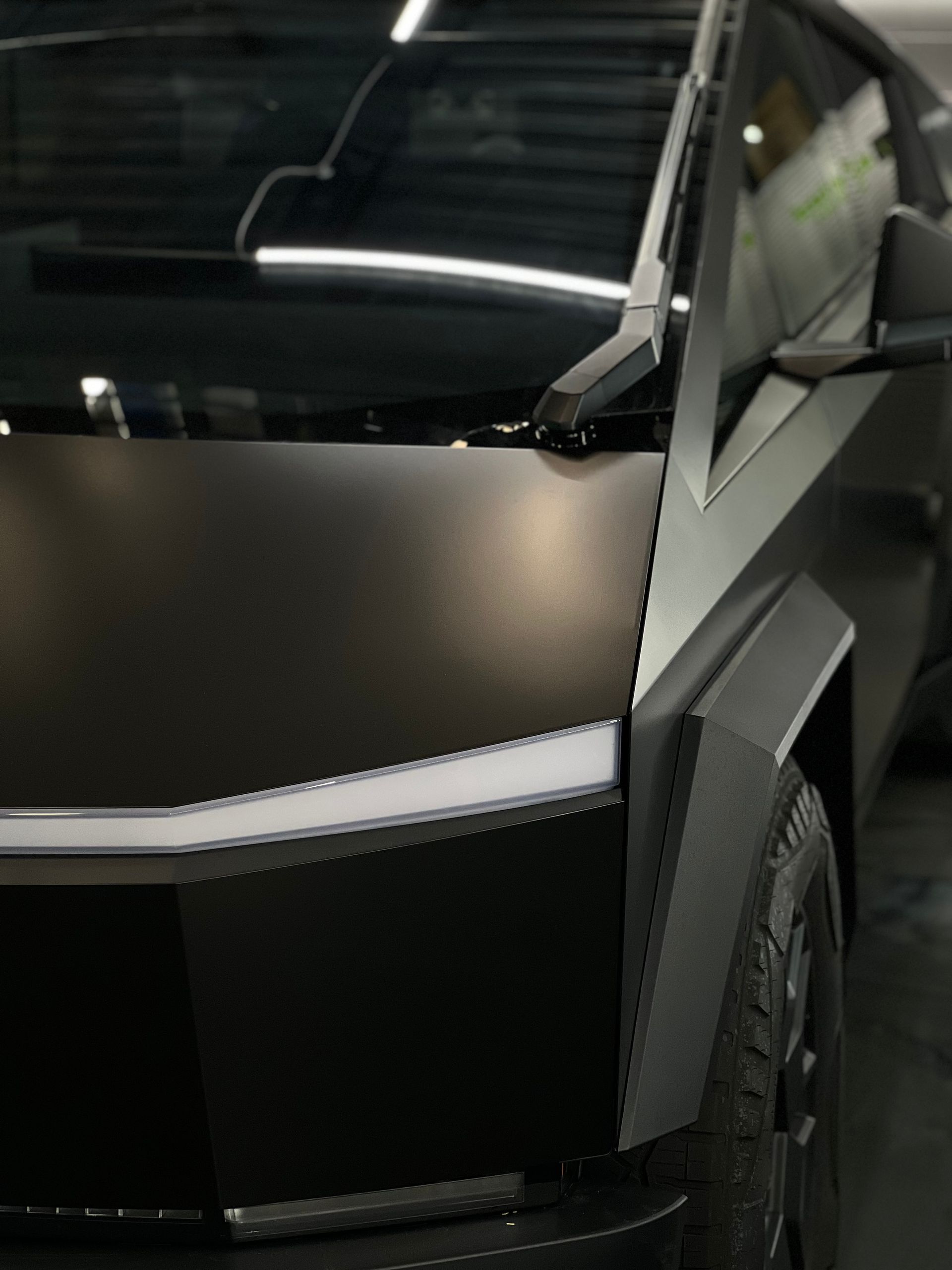 A black car is parked in a garage with the door open