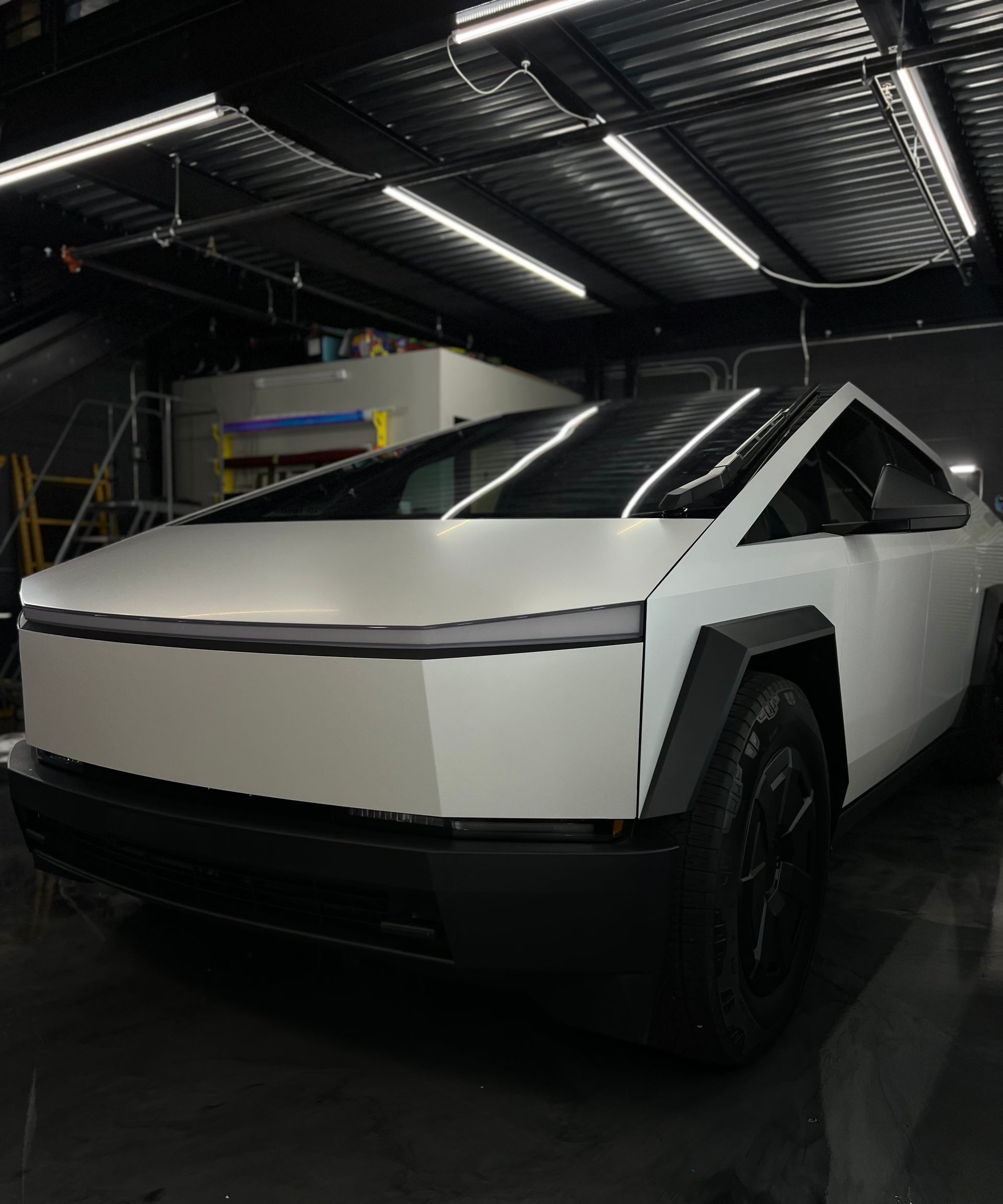 A white tesla cybertruck is parked in a garage.