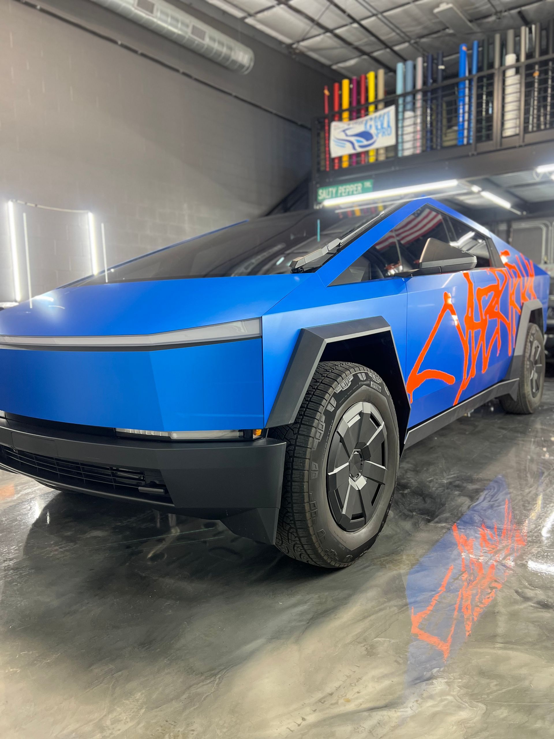 A blue tesla cybertruck is parked in a garage