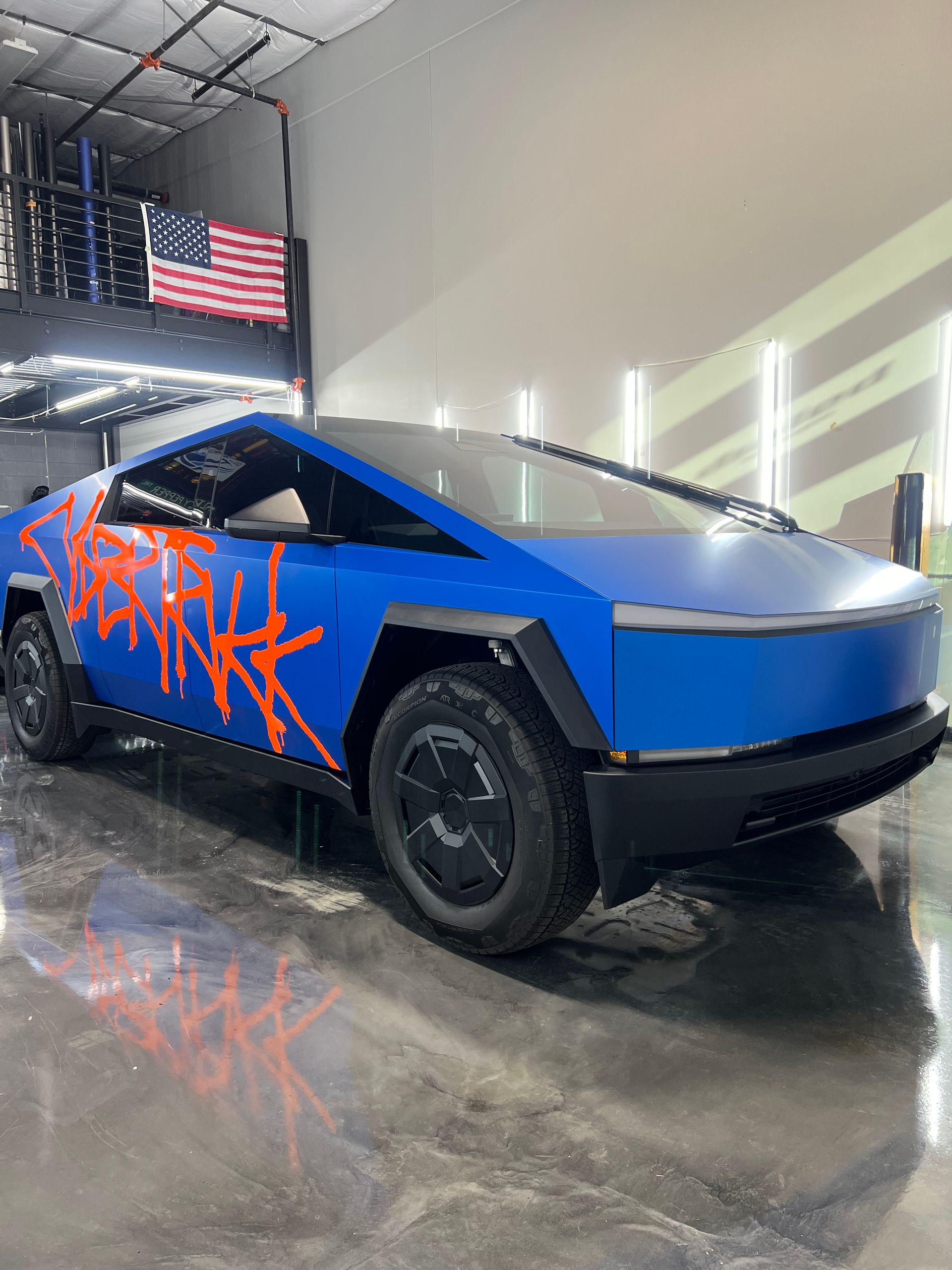 A blue tesla cybertruck is parked in a garage.