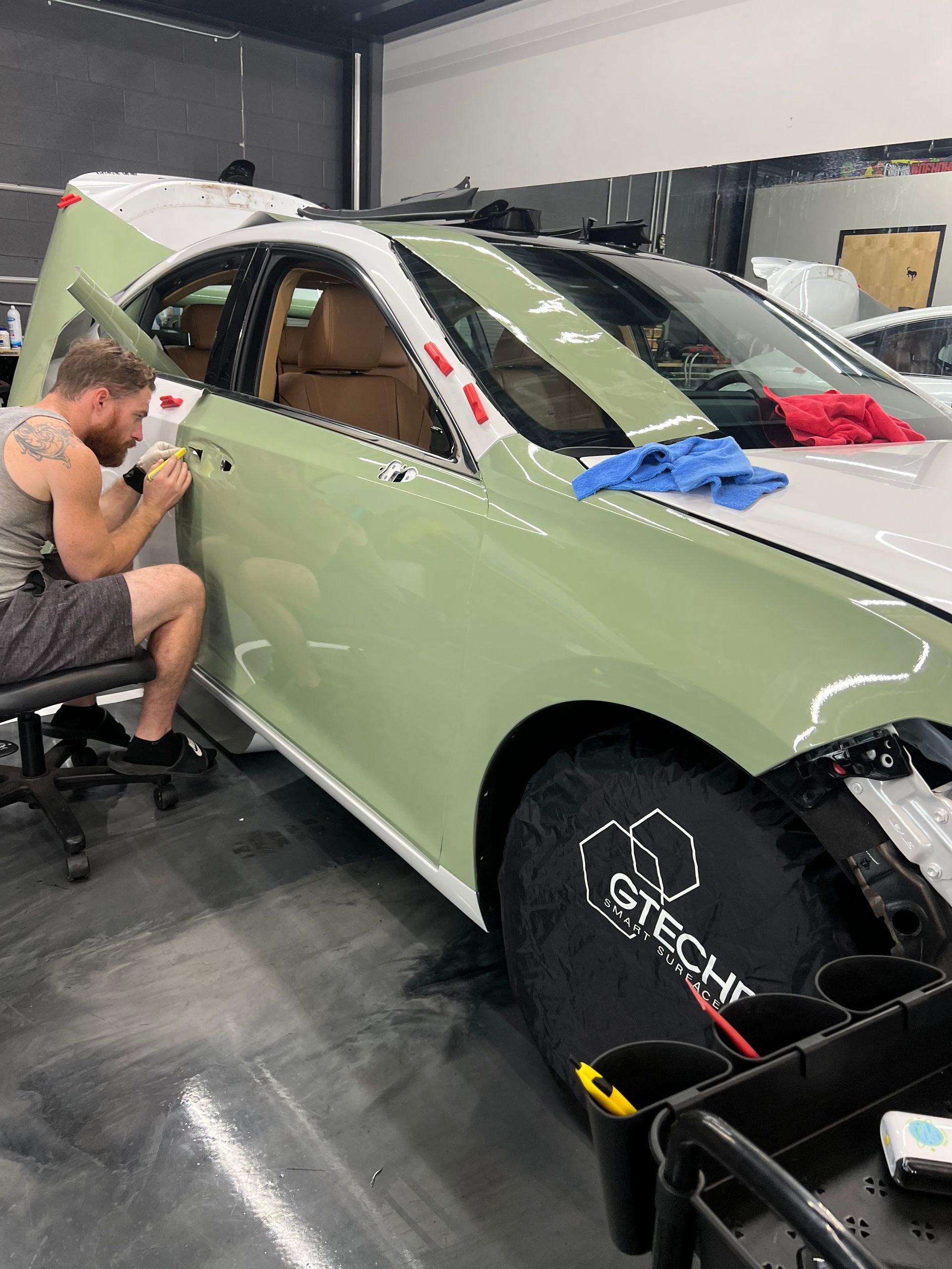 A man is working on a green car in a garage.