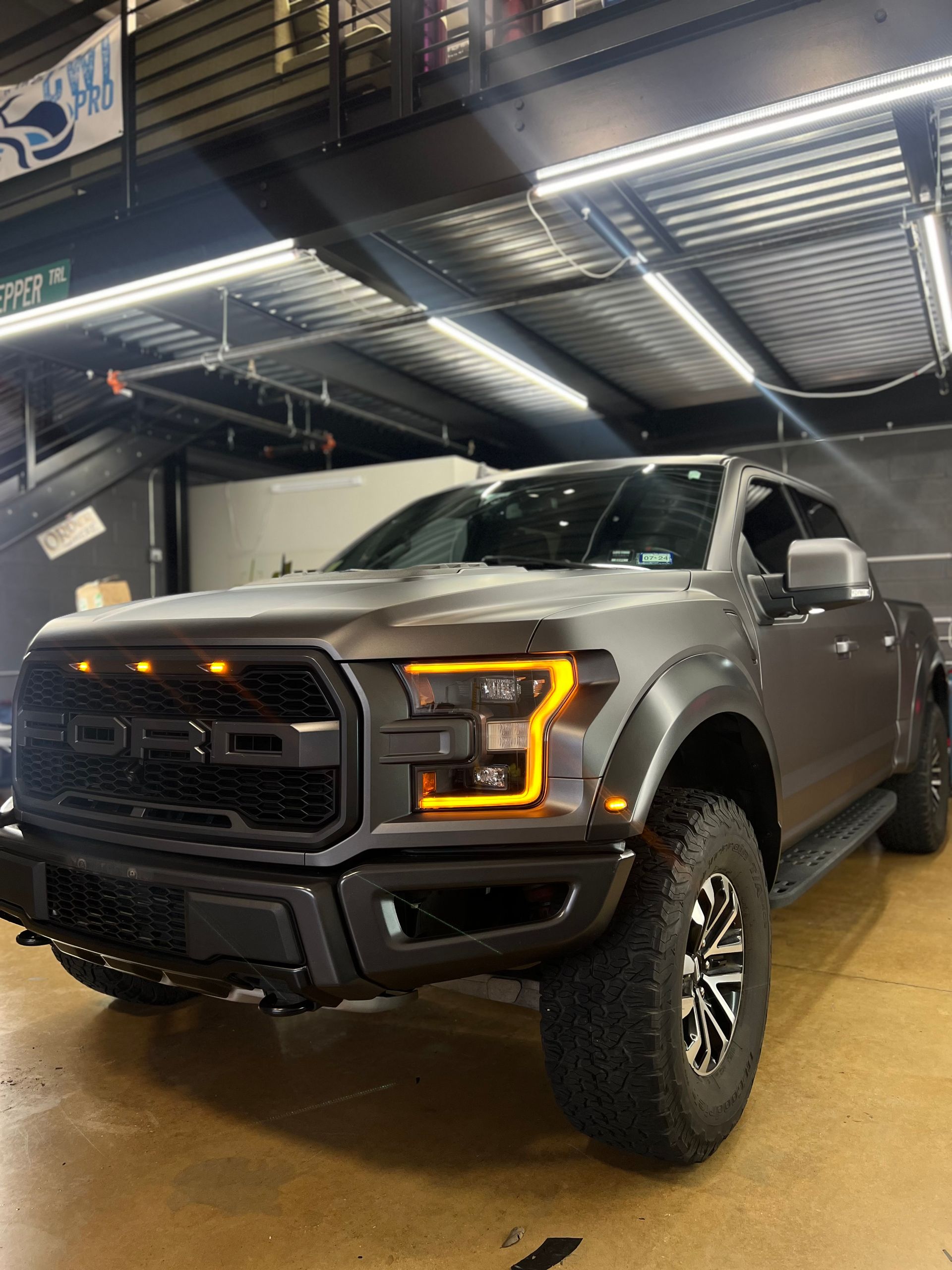 A ford raptor truck is parked in a garage.