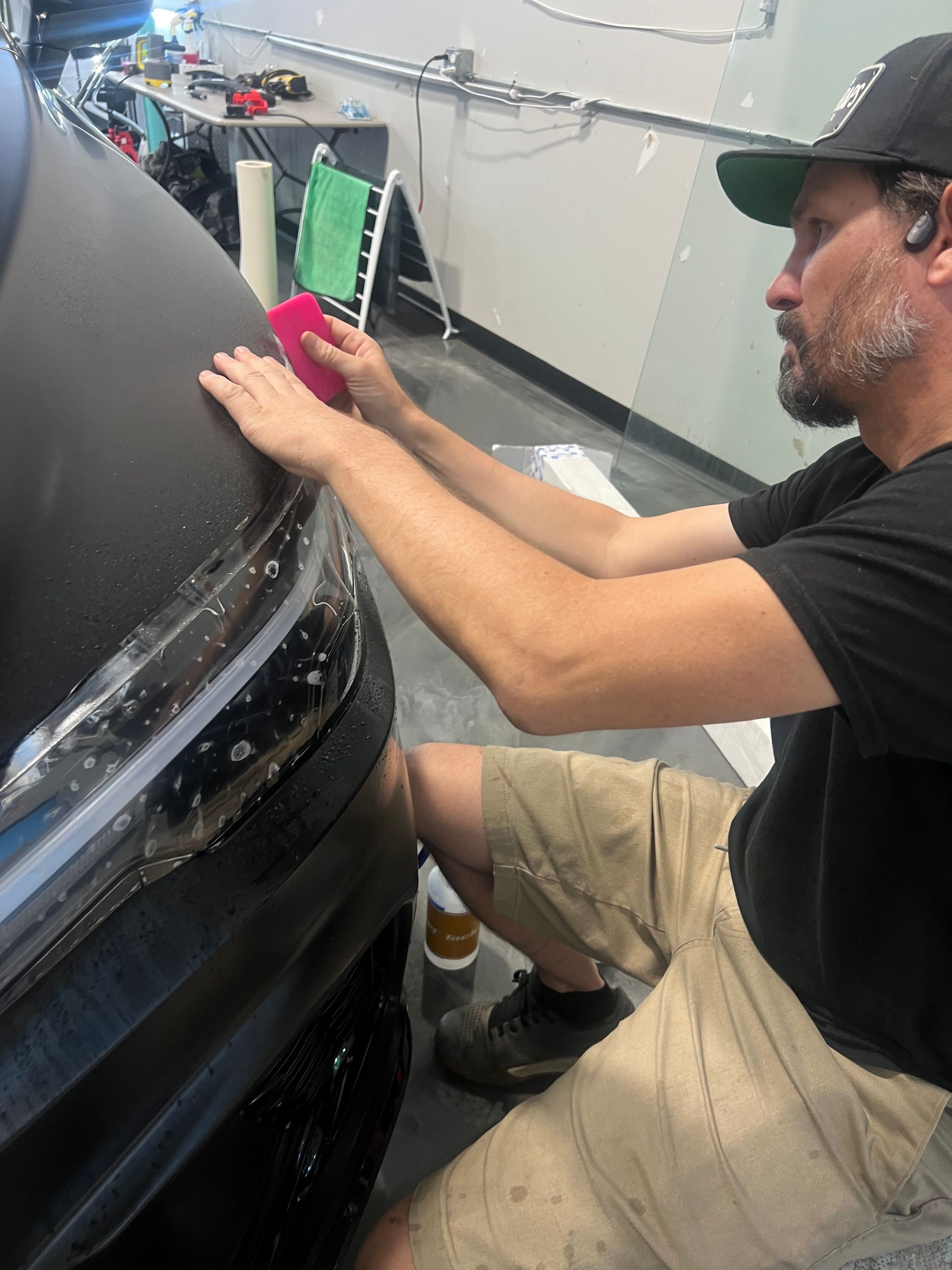 A man is wrapping a car with a sponge in a garage.