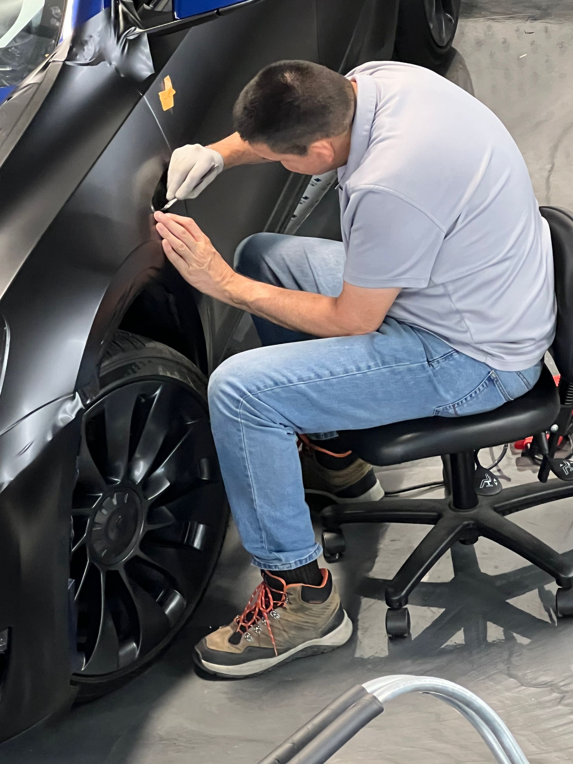 A man is sitting on a chair working on a car