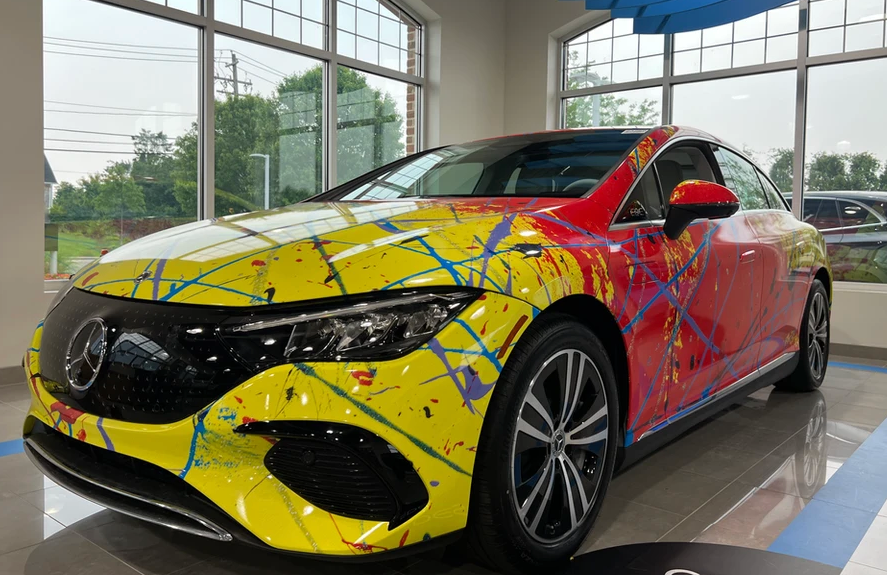 A yellow and red mercedes benz eqs is sitting in a showroom.