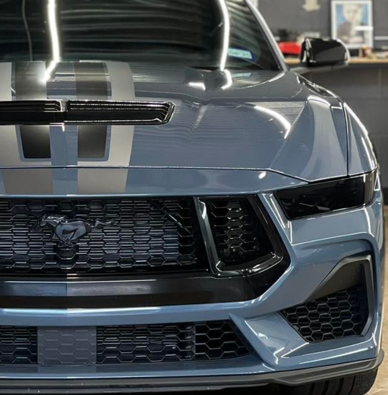 A gray mustang with black stripes on the hood