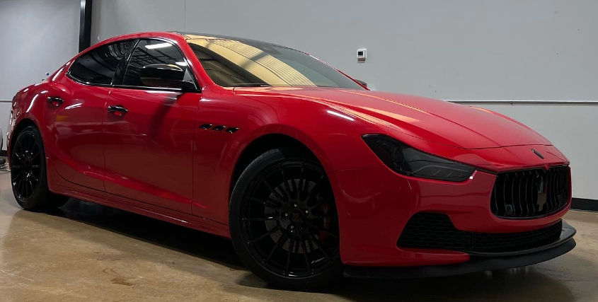 A red maserati ghibli is parked in a garage.