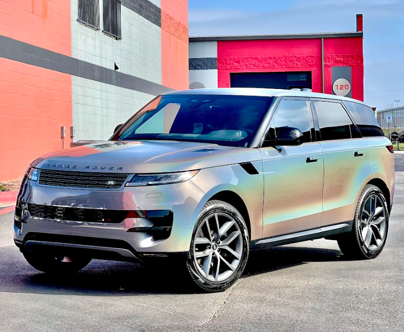 A silver range rover is parked in front of a building.