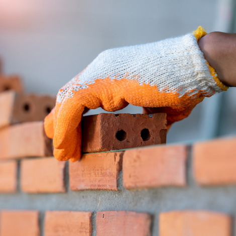 a man is laying bricks on a wall .