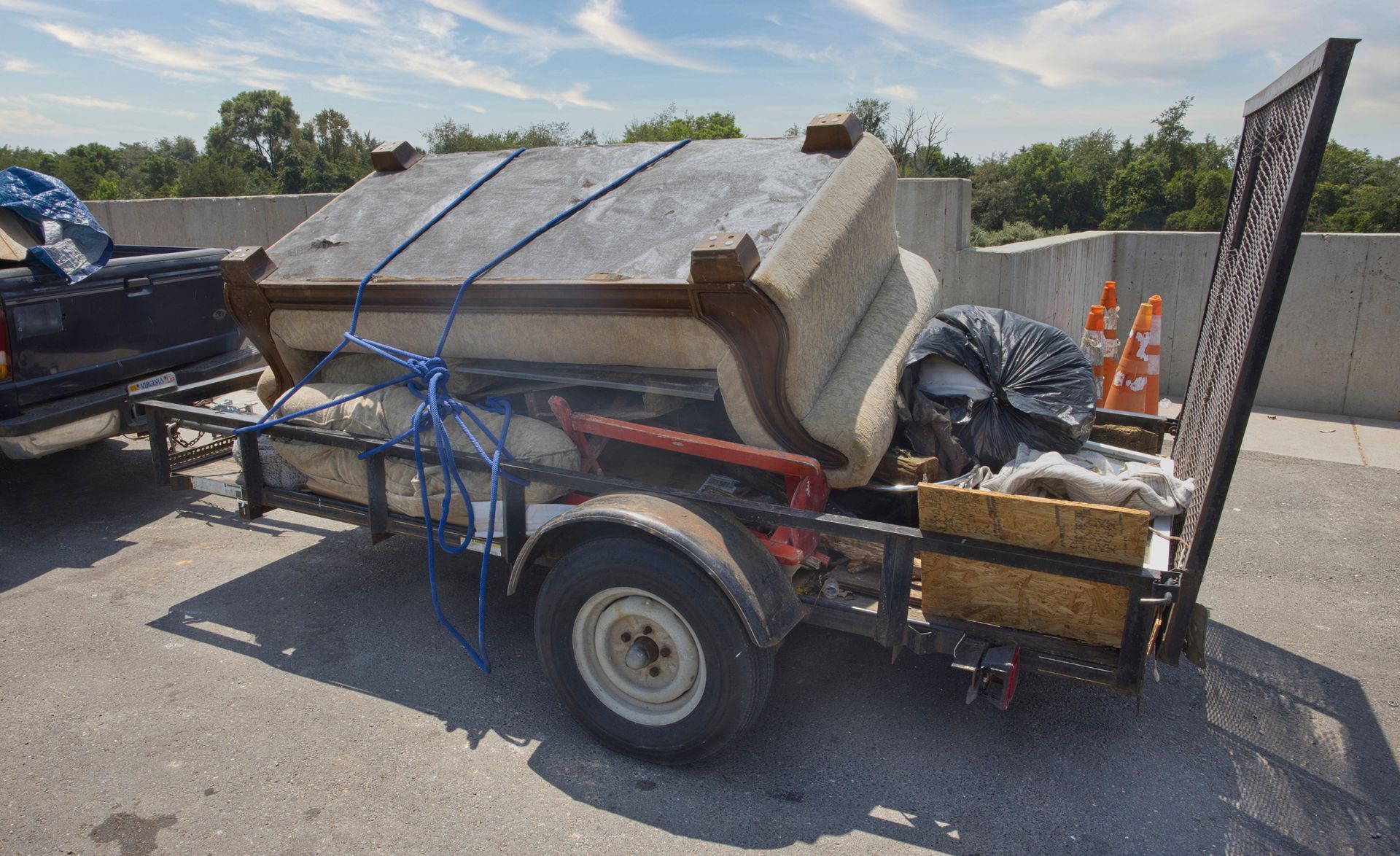 Trailer loaded with old furniture and trash; blue rope secures items.