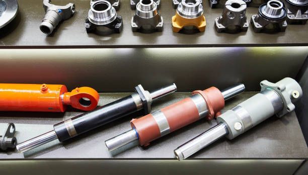 There are many different types of hydraulic cylinders on display on a shelf.