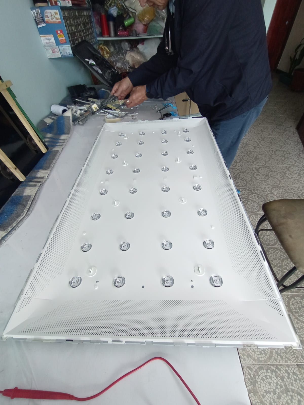 Persona trabajando en el panel de retroiluminación de un televisor.